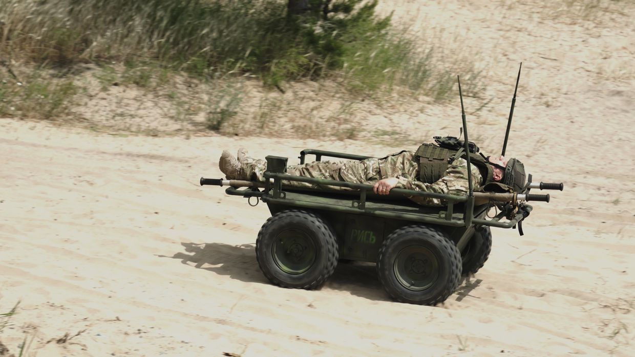 Ukrainian Rys ground drone carrying a wounded soldier on a stretcher across sandy terrain