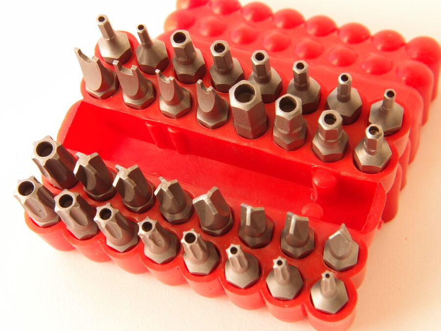 A security screwdriver bit set in a red plastic holder, its rows of bits carrying a range of tamper-resistant tips, including security Torx bits with the center-pin hole and hex sockets